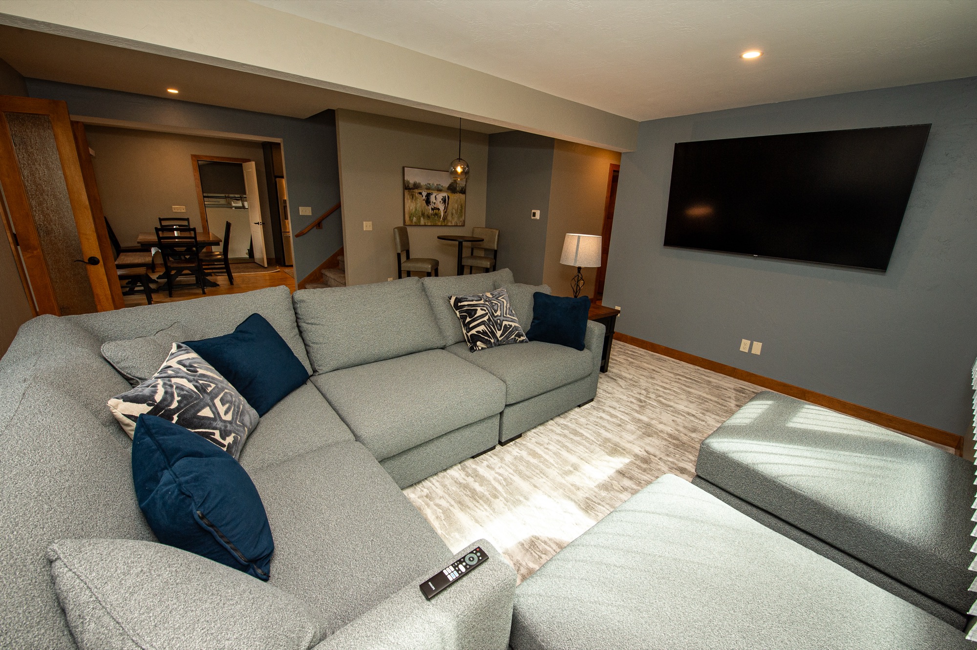 Lower-level living room with sectional sofa and wall-mounted TV