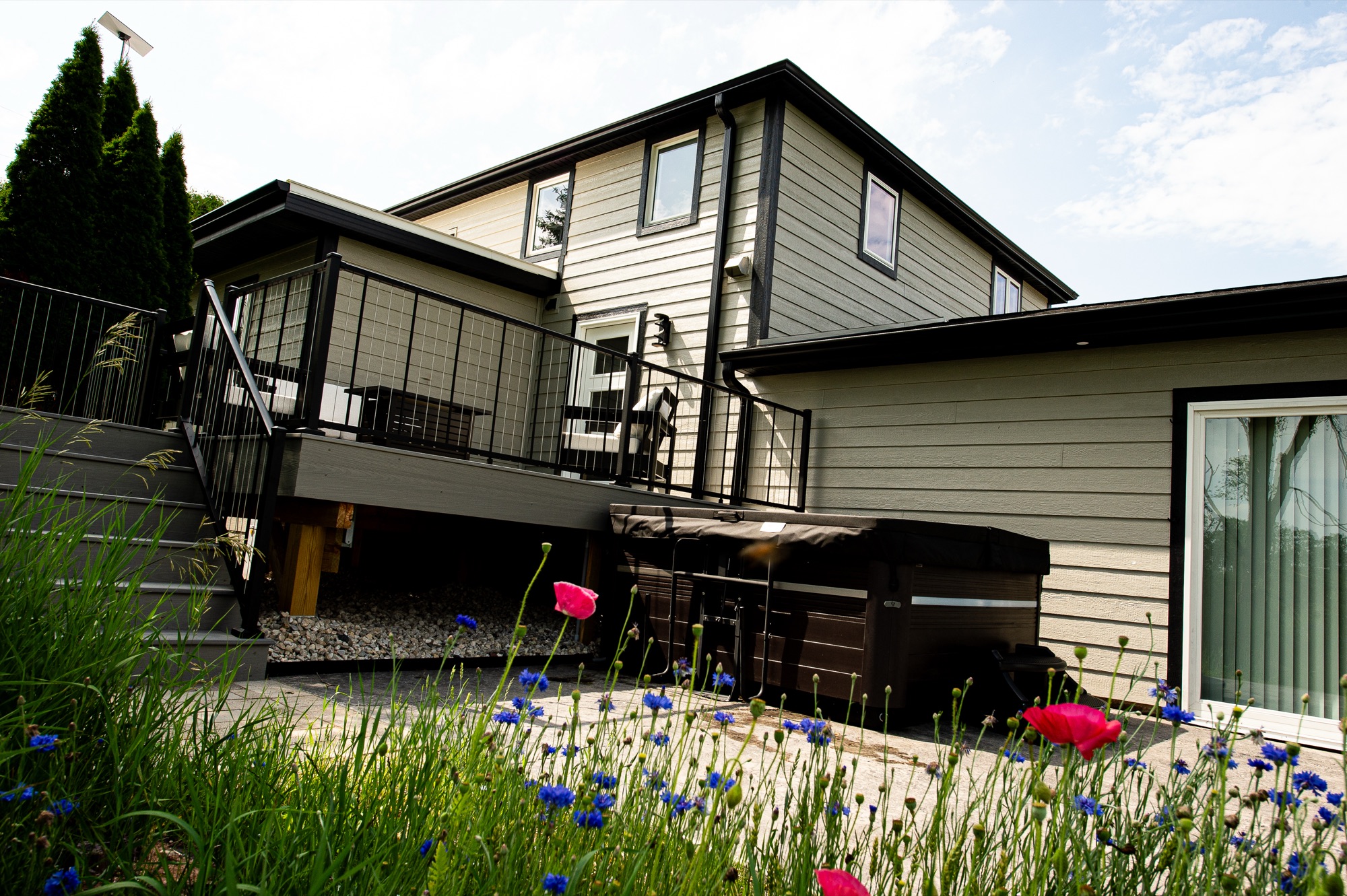 Back of Mullet Manor with the private hot tub and wildflowers in bloom