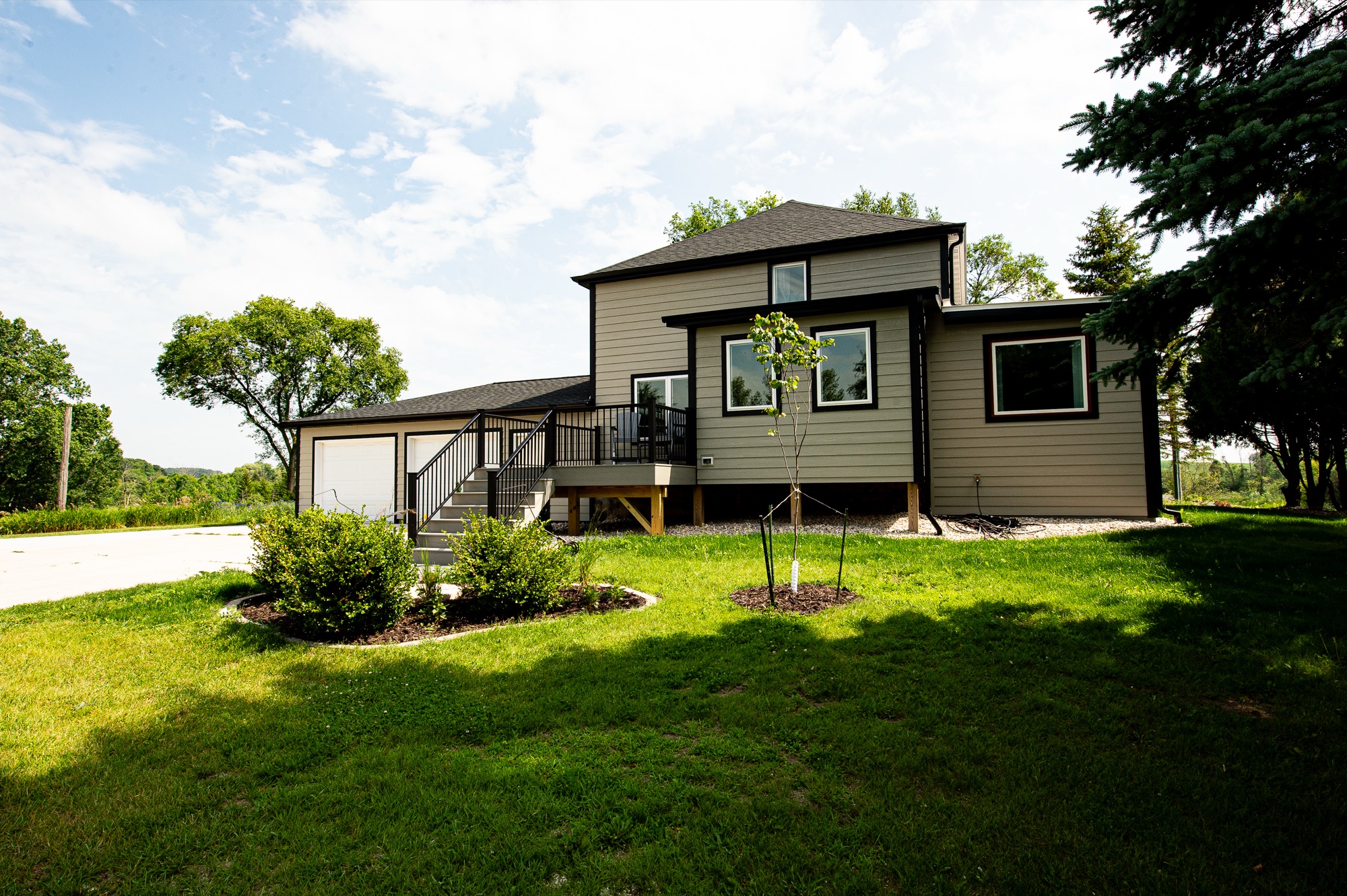 Front exterior of Mullet Manor with attached garage and summer landscaping